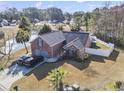 A lovely aerial view showcases a brick home, mature trees, an in-ground irrigation system, and a picturesque waterfront at 305 Duel Ct., Myrtle Beach, SC 29588