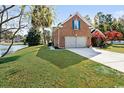 A neatly landscaped brick home with an attached garage is complemented by lush greenery and a serene lake view at 305 Duel Ct., Myrtle Beach, SC 29588