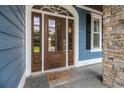 Close-up of an elegant wood front door with glass panels, stone accents, and a welcoming mat at 1201 Surf Pointe Dr., North Myrtle Beach, SC 29582