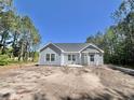 The back of a charming single-story home is visible under a clear blue sky with some trees at 6944 Highway 66, Loris, SC 29569