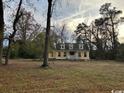Charming yellow home with a welcoming porch surrounded by mature trees in a large yard at 2708 Main St., Loris, SC 29569