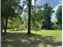 Charming yellow home with a welcoming porch, nestled among mature trees on a sprawling green lawn at 2708 Main St., Loris, SC 29569