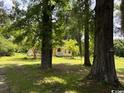 Charming yellow home with a welcoming porch, nestled among mature trees on a private lawn at 2708 Main St., Loris, SC 29569