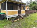 Charming yellow house featuring a screened-in porch and a wooden deck with planter boxes below at 2708 Main St., Loris, SC 29569