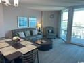 Cozy living room featuring a comfortable sofa, accent chair, and sliding glass doors to the balcony at 2301 S Ocean Blvd. # 1002, North Myrtle Beach, SC 29582