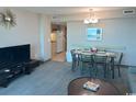 Spacious living area adjacent to dining area and featuring a TV, carpet and views to the kitchen at 2301 S Ocean Blvd. # 1002, North Myrtle Beach, SC 29582