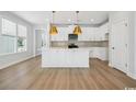 Modern kitchen featuring white cabinets, a center island with gold pendants and hardware, and stainless steel appliances at 2620 Hillbourne Loop, North Myrtle Beach, SC 29582