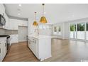 Bright kitchen with white cabinets, gold hardware, stainless steel appliances, and a large center island with a sink at 2620 Hillbourne Loop, North Myrtle Beach, SC 29582