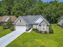 Aerial view of a brick home with a spacious lawn and a two car garage in a lush neighborhood at 765 Ashley Manor Dr., Longs, SC 29568
