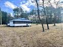 View of a home with a screened porch and metal roof set in a natural, wooded setting at 1451 Cane Branch Rd., Loris, SC 29569