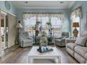 Bright living room featuring a large window with blinds, comfortable seating, and wood flooring at 5910 Lazio Ct. # 5910, Myrtle Beach, SC 29579