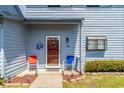 Inviting front porch with red door, crab decor, and colorful chairs set amidst well-maintained landscaping at 775 Plantation Dr. # 59, Little River, SC 29566