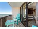 Balcony view with blue chairs and table with ocean scenery and living room access at 2311 S Ocean Blvd. # 1125, Myrtle Beach, SC 29577