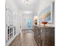 Bright hallway featuring hardwood floors, a decorative console table, and glass-paneled doors at 6550 Anterselva Dr., Myrtle Beach, SC 29572