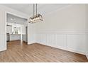 Open dining room with wood floors and decorative wainscoting, flowing seamlessly into the adjacent kitchen at 800 Caines Landing Rd., Conway, SC 29526