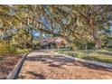 Inviting brick driveway leading to a beautifully landscaped home with mature trees and manicured greenery at 118 Oatland Lake Rd., Pawleys Island, SC 29585