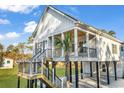 Beautiful elevated coastal home featuring a spacious porch, wooden ceiling, and verdant landscaping at 33 Captains Pl, Murrells Inlet, SC 29576