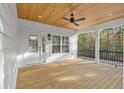 Covered porch with stained wood planking ceiling and floors, black railing, and peaceful wooded view at 33 Captains Pl, Murrells Inlet, SC 29576