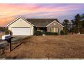 House exterior at sunset, featuring a brick facade and attached garage at 350 Blue Rock Dr., Longs, SC 29568