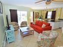 Comfortable living room features a bright orange sofa, two chairs, TV, and sliding glass door to a balcony at 507 S Ocean Blvd. # 201, North Myrtle Beach, SC 29582
