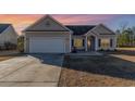 Charming single-story home with a well-lit entrance, two-car garage, and a neatly maintained driveway as the sun sets at 817 Payne Ct., Conway, SC 29526