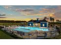 Community pool with a blue clubhouse, plenty of lounge chairs, and a sunset view at 2204 Flatleaf Ct, Longs, SC 29568