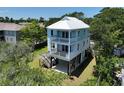 Stunning three-story coastal home with double decks and a bright metal roof, nestled among mature trees at 48 Furman Ln., Pawleys Island, SC 29585
