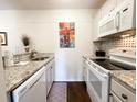 Efficient galley-style kitchen boasting granite countertops and white appliances at 178 Salt Marsh Circle # 30-E, Pawleys Island, SC 29585