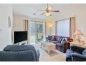 Bright living room featuring a ceiling fan, neutral carpet, and sliding glass doors to a patio at 820 Fairway Dr. # 1605, Longs, SC 29568