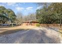 Brick ranch house with a gravel driveway and mature trees at 1043 Holt Rd., Conway, SC 29526