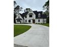 Two-story house with white brick exterior, black roof, and a large driveway at 101 Green Lake Dr., Myrtle Beach, SC 29572