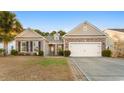 Tan house with a two-car garage and mature palm trees at 645 Lafayette Park Dr., Little River, SC 29566