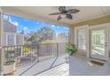Inviting balcony featuring a ceiling fan, potted plants, and views of a tree-lined street, perfect for relaxation at 1609 Harbor Dr., North Myrtle Beach, SC 29582