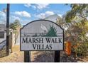 The Marsh Walk Villas sign features lovely vegetation and a blue sky background at 310 Marsh Pl. # 108, Garden City Beach, SC 29576