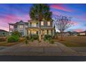 Charming two-story home featuring a welcoming front porch and beautifully landscaped yard with palm trees at dusk at 836 Crystal Water Way, Myrtle Beach, SC 29579