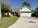 Front view of a brick house with a two-car garage and landscaping at 635 Bucks Trail, Longs, SC 29568