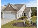 Tan colored exterior of house with two car garage and landscaped yard at 7015 River Bridge Ct, Myrtle Beach, SC 29579