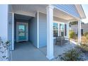 Front entrance with teal door, white columns, and a small bench at 2024 Willow Run Dr., Little River, SC 29566