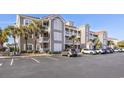 Condo exterior featuring multiple floors and car parking in front of the building with palm trees at 4210 Coquina Harbour Dr. # A-16, Little River, SC 29566