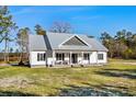 White farmhouse with gray metal roof, large yard, and sunny day at 5300 Juniper Bay Rd., Conway, SC 29527