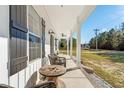 Front porch with white columns, wicker chairs, and a wooden table at 5300 Juniper Bay Rd., Conway, SC 29527