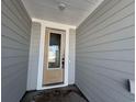 Exterior shot of home's front door and covered entry, highlighting the light gray siding at 1300 Crested Iris Way, North Myrtle Beach, SC 29582