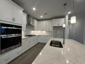 Bright kitchen with stainless steel appliances, white cabinets, a marble countertop island, and pendant lighting at 1305 Crested Iris Way, North Myrtle Beach, SC 29582