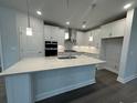 Modern kitchen featuring a large island, white cabinets, stainless steel appliances and stylish pendant lighting at 1305 Crested Iris Way, North Myrtle Beach, SC 29582