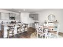 Open kitchen with gray cabinets, an island with barstool seating, and adjacent dining area at 536 Duvall St., Longs, SC 29568