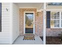 Welcoming front entry featuring a glass door, brick accents, and a 'Welcome to our Home' doormat at 5933 Rahnavard Blvd., Myrtle Beach, SC 29588