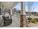 Relaxing front porch with stone columns and wicker chairs at 1400 Rainsbrook Ct., Conway, SC 29526