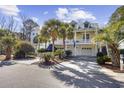 Two-story home with a large porch, two-car garage, and lush landscaping at 65 Harbourreef Dr., Pawleys Island, SC 29585