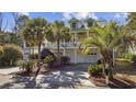 Two-story home with a two-car garage and mature palm trees at 65 Harbourreef Dr., Pawleys Island, SC 29585