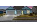 Inviting light blue home with a two-car garage, well-maintained lawn, and colorful sunset background at 1410 Saw Palmetto St., North Myrtle Beach, SC 29582